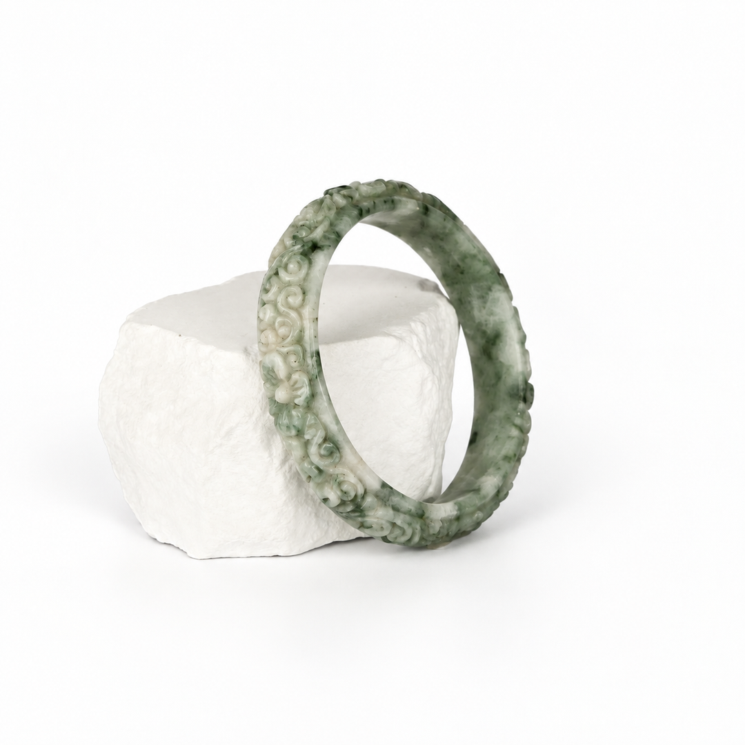 Hand-carved moss-in-snow Jadeite bangle, hero view on white stone